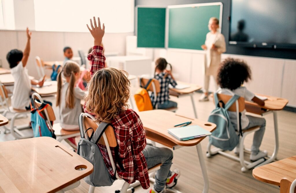 Crianças com a mão estendida em aula
