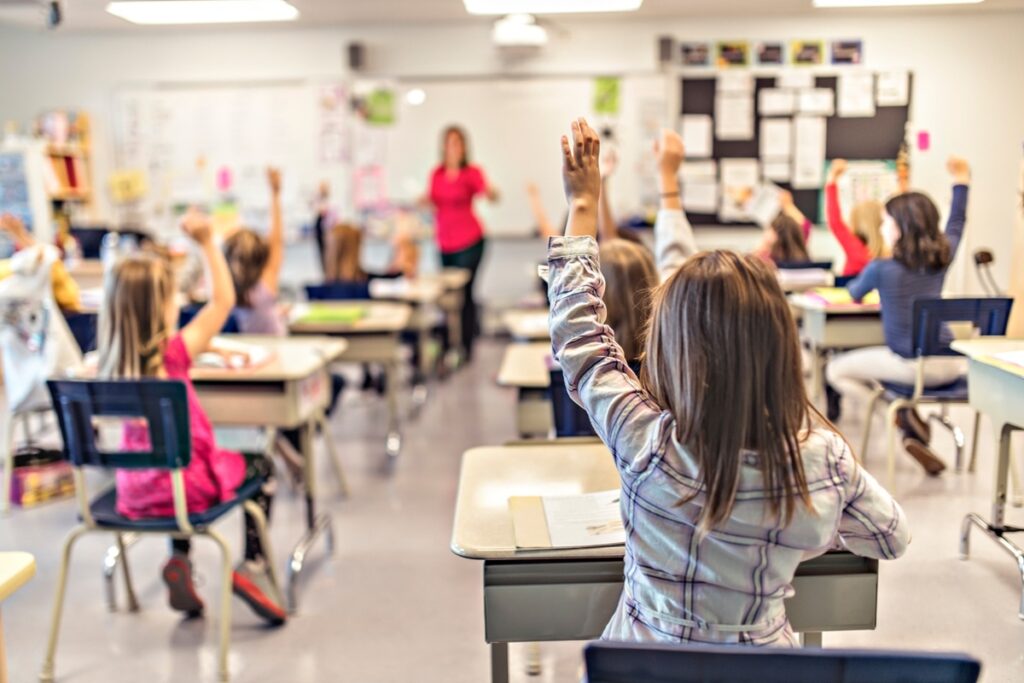 Crianças com a mão estendida em aula