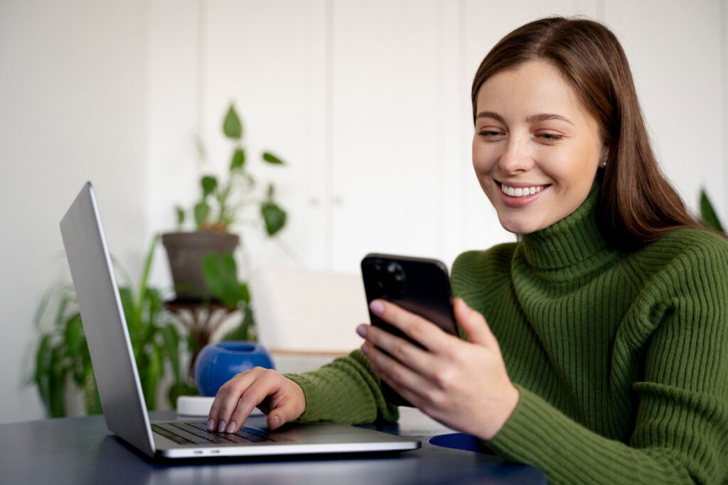 Mulher usando WhatsApp Web no laptop; multitarefa; escritório doméstico.