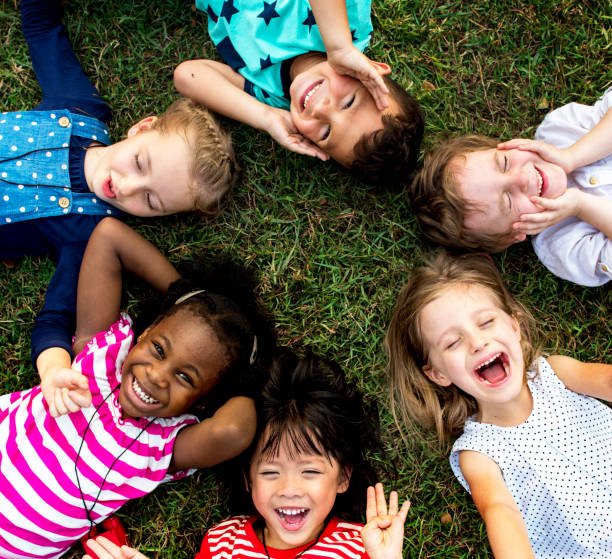 Group of kindergarten kids lying on the grass at park and relax with smiling