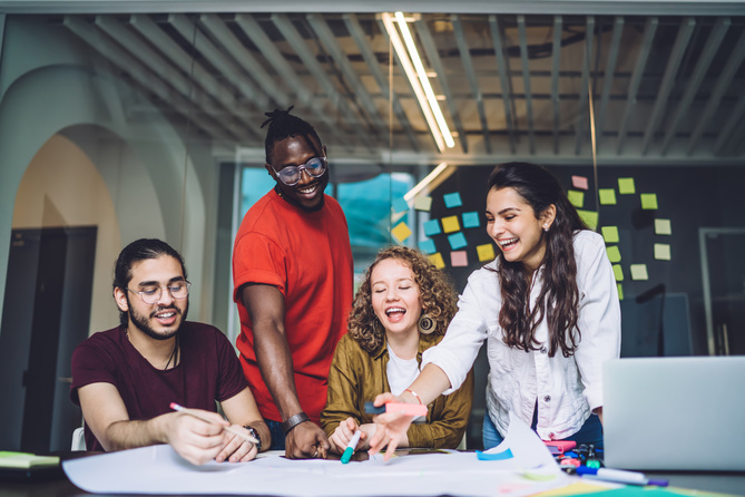 Young creative dedicated startup team preparing for presentation of business project and discussing ideas while working together at table with paper draft