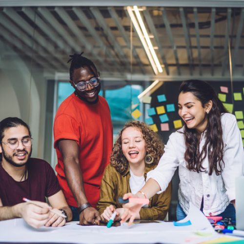 Young creative dedicated startup team preparing for presentation of business project and discussing ideas while working together at table with paper draft