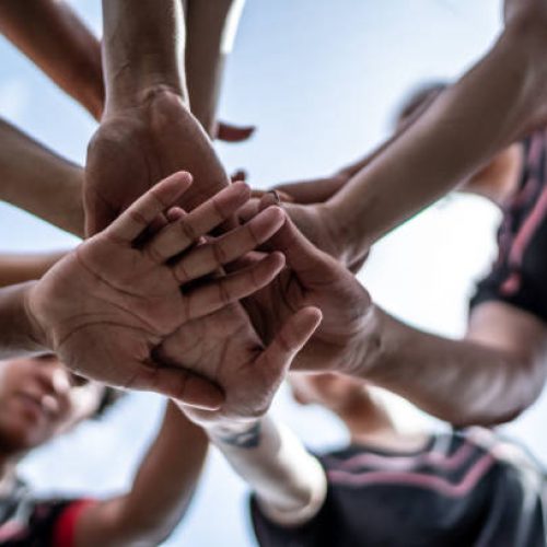 Close-up of female soccer team stacking hands in the field