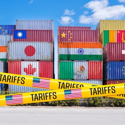 Shipping containers adorned with global flags, barricaded by US Tariffs tape (Montage)
